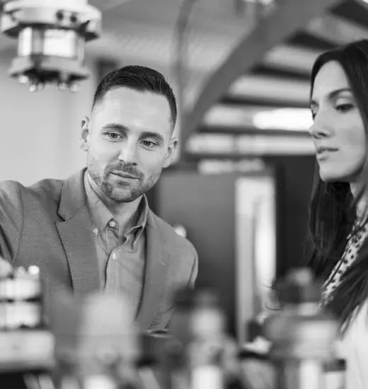 Businessman and businesswoman examining workpieces in factory Businessman and businesswoman examining workpieces in factory